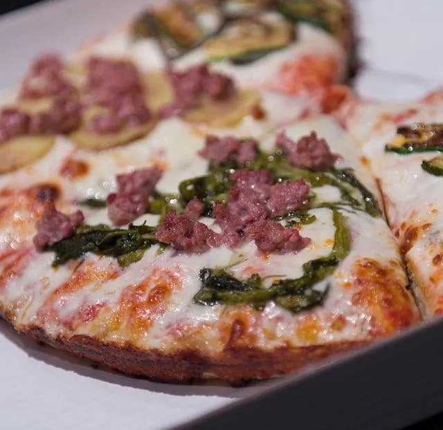 Pizza al trancio appena sfornata con ingredienti freschi